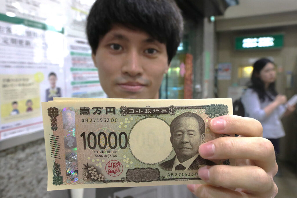 A man holds a new 10,000 yen note at a bank in Saitama on the day the new banknotes were issued on July 3, 2024. (Photo by JIJI PRESS / AFP)