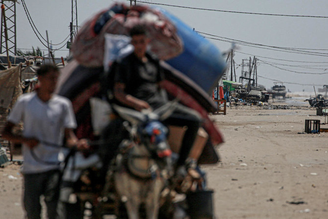An Israeli tank takes position in the background as displaced Palestinians evacuate from the northwestern outskirts of Rafah in the southern Gaza Strip on June 28, 2024. (AFP file photo)