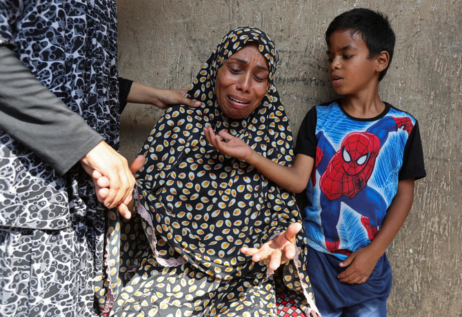 A Palestinian woman reacts next to a child after an Israeli air strike on a UN school sheltering displaced people in Nusairat in central Gaza Strip, July 14, 2024. (Reuters)