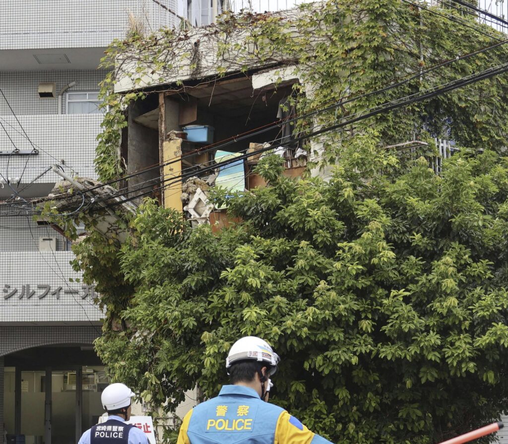 Police stand outside a damaged building following an earthquake in Miyazaki, western Japan, Thursday, Aug. 8, 2024.(Kyodo News via AP)