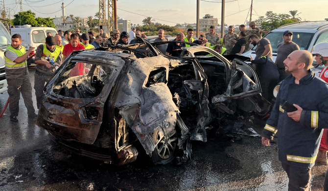Lebanese firefighters and security forces work around a burnt car following an Israeli strike in the southern Lebanese city of Sidon on August 9, 2024. (AFP)
