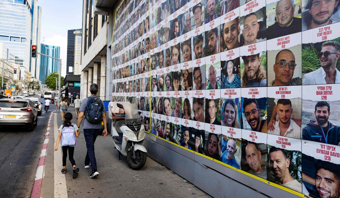 People walk past posters of Israelis held hostage by Palestinian militants in Gaza since the October 7 attacks, in Tel Aviv on August 11, 2024, amid the ongoing conflict in the Gaza Strip between Israel and the militant Hamas movement. (AFP)