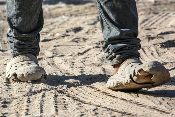 A Palestinian walks in damaged shoes in Khan Yunis, on the southern Gaza Strip on July 6, 2024. (AFP)