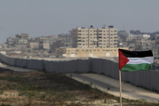 A Palestinian flag is seen with the background of a section of the wall in the Philadelphi corridor between Egypt and Gaza, on the background, near the southern Gaza Strip town of Rafah. (AP)
