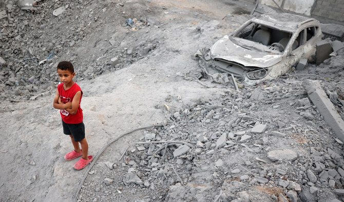 A young Palestinian boy stands near a car buried in rubble in the vicinity of a building shortly after it was levelled by Israeli bombing in the Nuseirat refugee camp in the central Gaza Strip on August 22, 2024. (AFP/File)