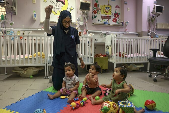A nurse entertains triplets Najoua, Nour, and Najmeh. (AFP)