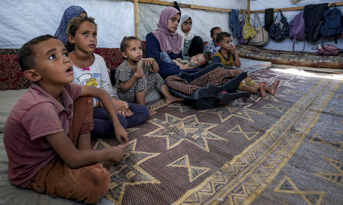 Displaced infant Abdel-Rahman Abuel-Jedian, 11-month-old, who suffers from polio, is carried by his mother, center, at a makeshift tent camp in Deir al-Balah, central Gaza Strip, Tuesday, Aug. 27, 2024. (AP)