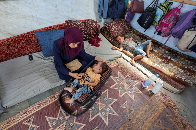 The mother of Palestinian boy Abdul Rahman Abu Al-Jidyan, who is the first person to contract polio in Gaza in 25 years, looks after him in their tent in Deir Al-Balah, central Gaza Strip on Aug. 28, 2024. (Reuters)