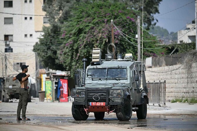 A Palestinian youth lifts his t-shirt up to show Israeli troops that he is unarmed during a military operation in Jenin in the north of the occupied West Bank on August 29, 2024.(AFP)