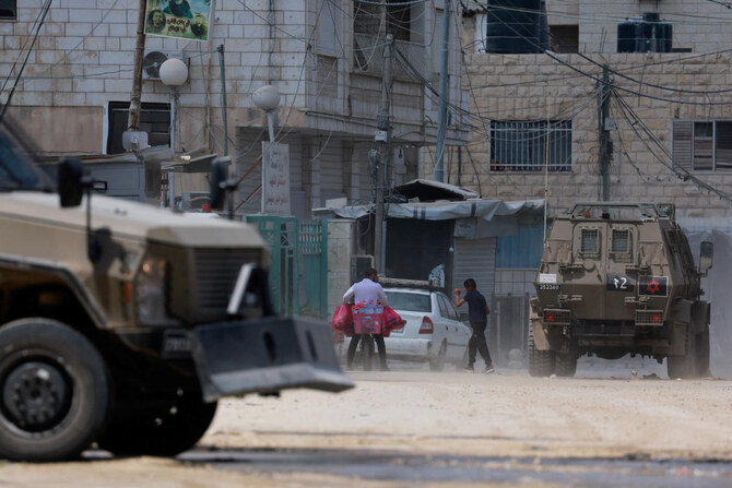 A Palestinian walks next to armored vehicles during an Israeli raid in Jenin, in the Israeli-occupied West Bank, August 31, 2024. (REUTERS)