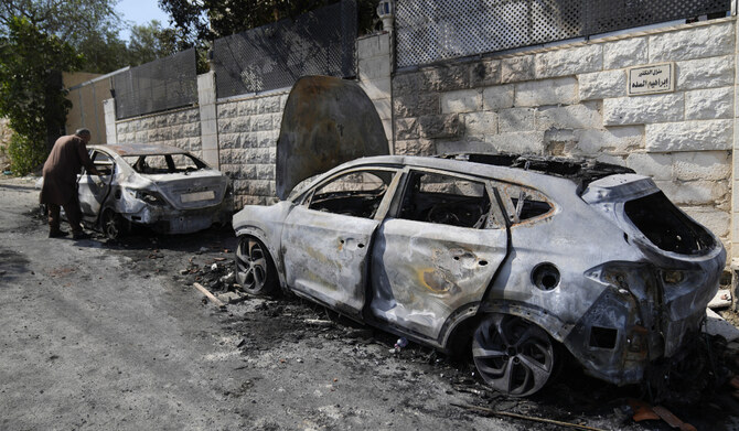 A Palestinian examines a torched vehicle, seen the morning after a rampage by Israeli settlers in the West Bank village of Jit, Friday, Aug. 16, 2024. (AP)