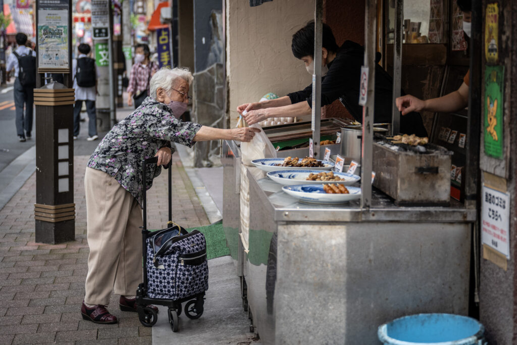 An elderly woman shops at a grilled chiken shop in Sugamo area of Tokyo on May 22, 2024. (AFP)