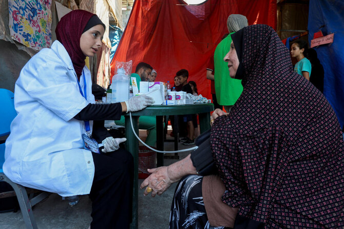 A medic checks the blood pressure of a Palestinian woman at a tent set up by Lobna Al-Azaiza, a Palestinian pediatrician providing free medical services to displaced Palestinians, near Al-Azaiza’s house, which was destroyed in an Israeli strike, in Deir Al-Balah on Aug. 12, 2024. (Reuters)