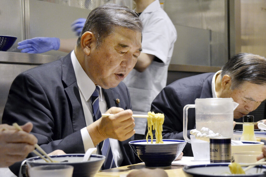 ISHIBA Shigeru and other LDP members eat a bowl of ramen noodles at a ramen shop in Tokyo, May 21, 2024. (Kyodo News via AP)