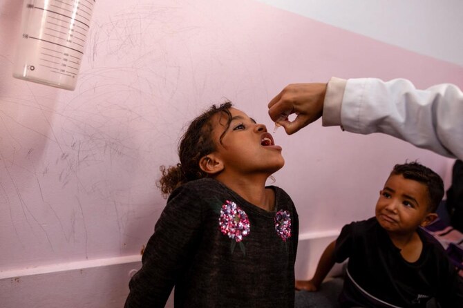 A young boy watches as a nurse administers Polio vaccine drops to a young Palestinian patient at the Nasser hospital in Khan Yunis in the southern Gaza Strip on August 31, 2024, amid the ongoing conflict between Israel and the Hamas militant group. (AFP)