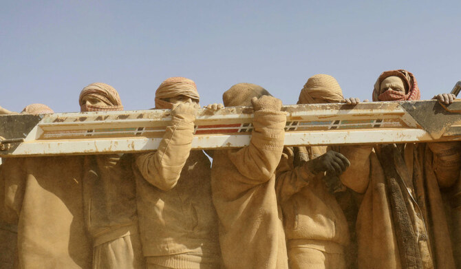 Men stand in the back of a truck as people who fled battles between Syrian Democratic Forces (SDF) and fighters from the Daesh group in the Syrian village of Baghuz, arrive after crossing a desert area to a region controlled by the SDF in the countryside of the Deir Ezzor province on January 26, 2019. (AFP)