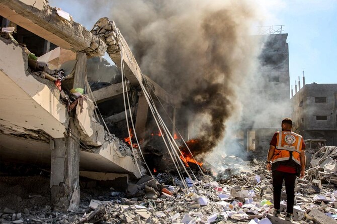A Palestinian civil defense member stands near a building on fire that was hit by Israeli bombardment in the Sheikh Radwan neighborhood in the north of Gaza City on Sept. 3, 2024. (AFP)