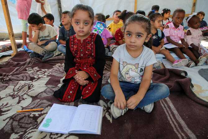 Palestinian students attend a class in a tent set up on the rubble of the house of teacher Israa Abu Mustafa, as war disrupts a new school year, in Khan Younis on Sept. 4, 2024. (Reuters)