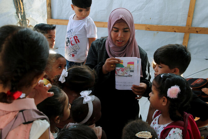 Palestinian teacher Israa Abu Mustafa gives a class to students inside a tent set up on the rubble of her house as war disrupts a new school year in Khan Younis, on Sept. 4, 2024. (Reuters)