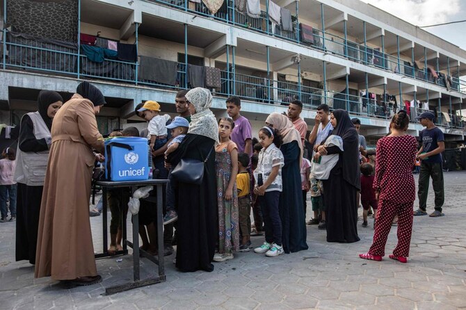People queue with their children for polio vaccinations at a make-shift camp for those displaced by conflict in a school run by the UNRWA in Khan Yunis in the southern Gaza Strip on Sept. 5, 2024. (AFP)