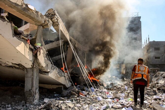 A Palestinian civil defence member stands near a building on fire that was hit by Israeli bombardment in the Sheikh Radwan neighbourhood in the north of Gaza City on September 3, 2024. (AFP)