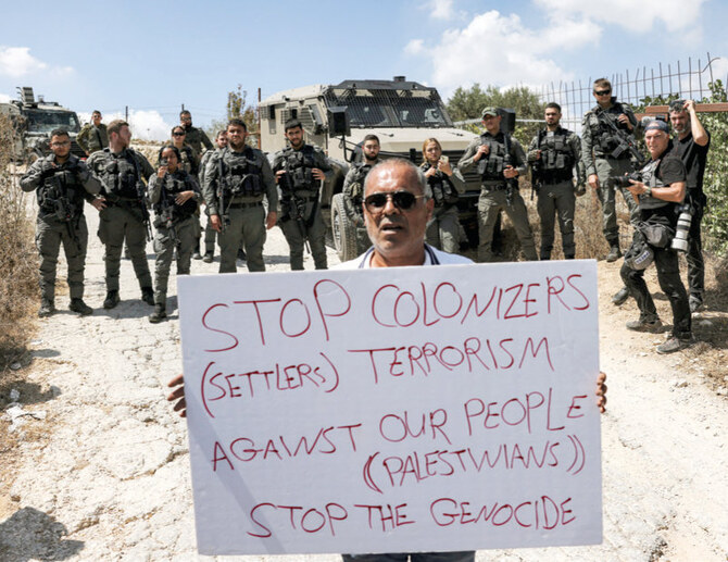 Demonstrators sit before Israeli border guards during a protest vigil in Beit Jala in the occupied West Bank on September 3, 2024 in solidarity with the Palestinian Kisiya family whose land was taken over by armed Israeli settlers planning to build a new outpost. (AFP)