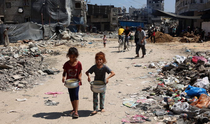 Palestinian children carry pots of soup near a food distribution point in the Jabalia refugee camp in northern Gaza Strip on August 21, 2024. (AFP/File)