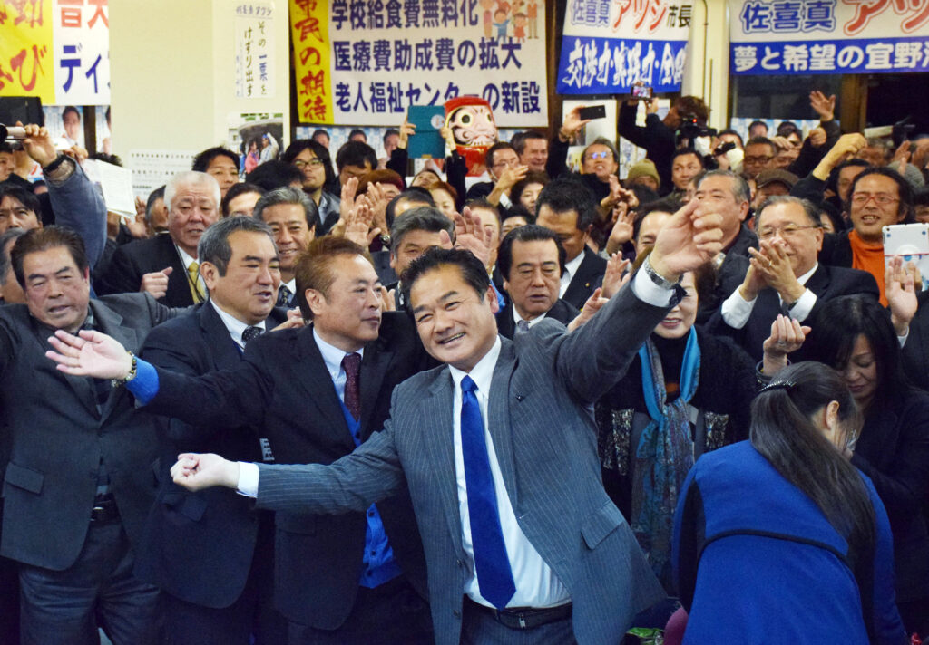 This picture taken on January 24, 2016 shows Okinawa's Ginowan city mayor Atsushi Sakima (C) dancing with his supporters after being re-elected as mayor of Ginowan at his campaign office in Ginowan, Japan's southern island of Okinawa. (AFP)
