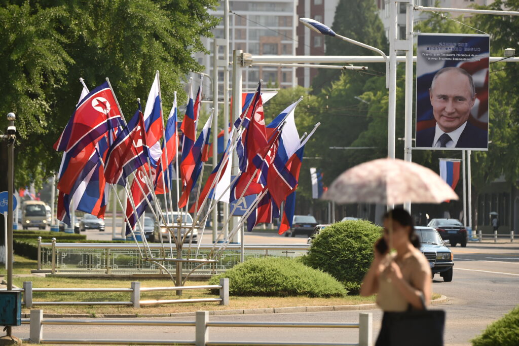 A portrait of Russian President Vladimir Putin is seen near national flags of North Korea and Russia in Pyongyang on June 20, 2024, displayed for Putin's summit with North Korea's Kim Jong Un where he won a pledge of