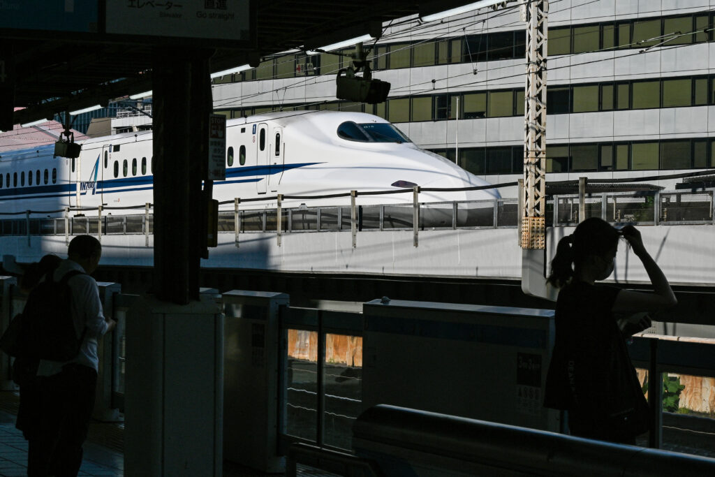 This photo taken on June 11, 2024 shows people waiting on a platform as a shinkansen bullet train passes by, at JR Yurakucho station in Tokyo. (AFP)