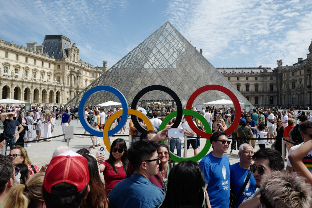 Visitors pose for pictures near the olympic rings in front of the Louvre Pyramid (Pyramide du Louvre) designed by Ieoh Ming Pei and the Olympic Rings, as part of the Paris 2024 Olympic Games in Paris on July 28, 2024. (AFP)
