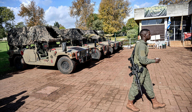 An Israeli army soldier walks with a cup and a cigarette past parked humvees on January 4, 2024 in the evacuated Kibbutz Dafna in northern Israel, about a kilometre away from the border with Lebanon. (AFP)