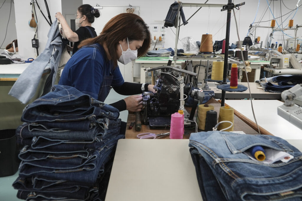 A seamstress works on denim trousers at Momotaro Jeans using a vintage sewing machine in Kojima. (AP Photo/Ayaka McGill)