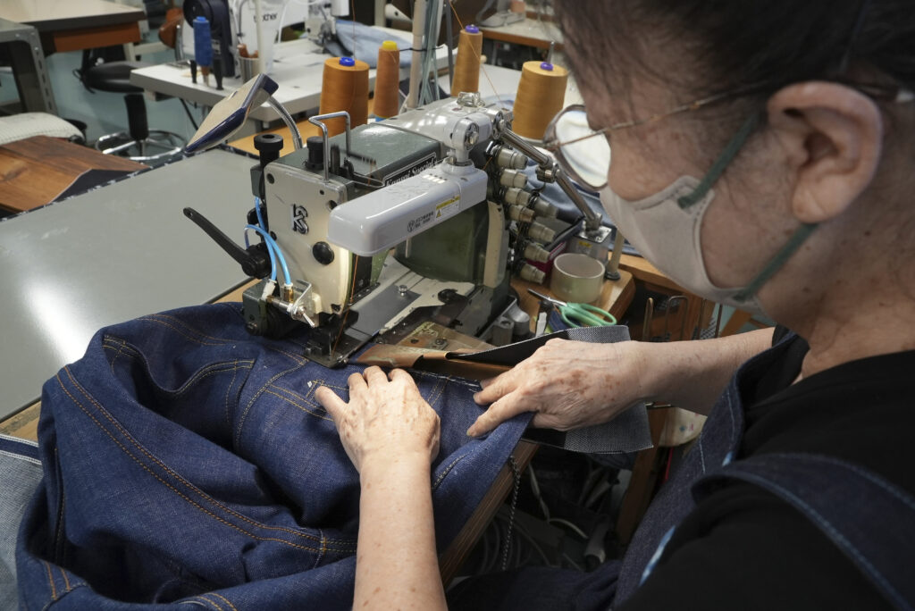 Naomi Takebayashi, a seamstress at Momotaro Jeans, sewing a pair of jeans in Kojima. (AP Photo/Ayaka McGill)