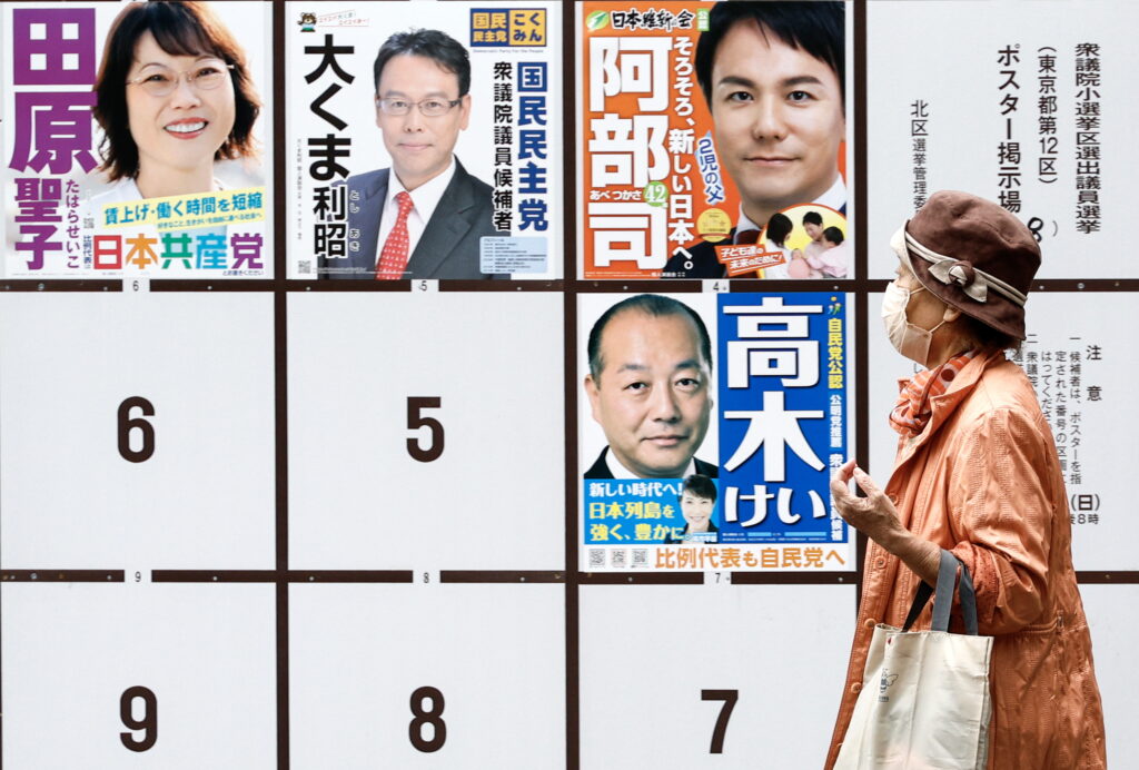 A woman walks past a board displaying campaign posters of candidates running for the upcoming general elections in Tokyo, Japan, 25 October 2024. (EPA)