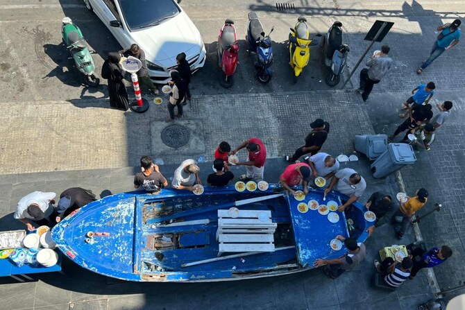 People who fled their homes in the south of Lebanon receive a portion of food aid being distributed by a restaurant in the southern city of Sidon on Sept. 29, 2024. (AFP)