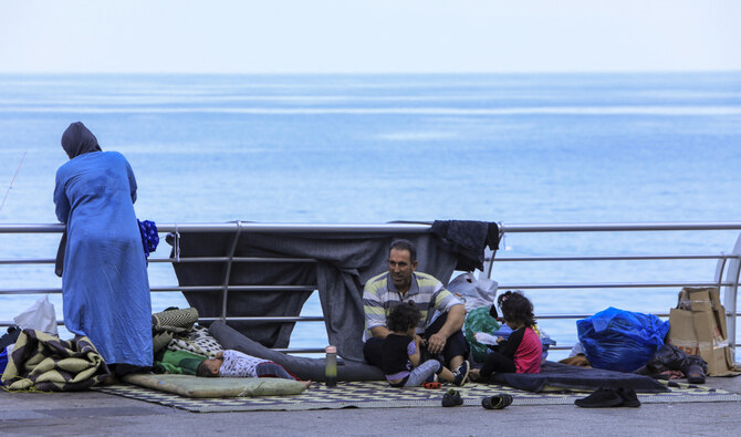 A displaced family sit with their belongings at central Beirut's Ain Al-Mreisseh seaside promenade on October 8, 2024. (AFP)
