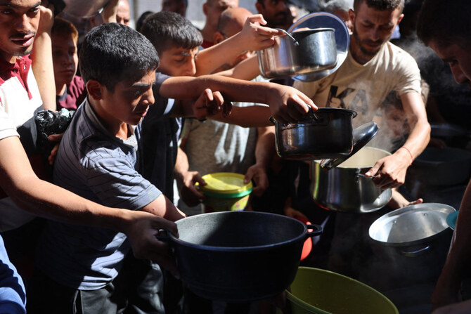 Displaced Palestinians queue to receive food rations, offered by a charity, in Gaza's Al-Shati refugee camp on October 17, 2024. (AFP)