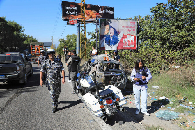 Journalists and security forces stand next to the wreckage of a car that was targeted in an Israeli drone attack on the Beirut-Damascus road in the area of Kahhale on October 24, 2024, amid the ongoing war between Israel and Hezbollah. (AFP)