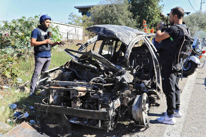 Journalists and security forces stand next to the wreckage of a car that was targeted in an Israeli drone attack on the Beirut-Damascus road in the area of Kahhale on October 24, 2024, amid the ongoing war between Israel and Hezbollah. (AFP)