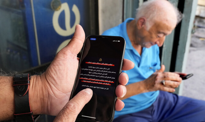 Men read mobile phone alerts telling residents of southern Lebanon not to return to their homes until further notice because of operations Israel says are targeting Hezbollah facilities in Beirut, Lebanon, Wednesday, Oct. 9, 2024. (AP)