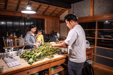 This photo taken on October 20, 2024 shows Rie Kato (left) and Toshiki Kato with their son Kuranosuke cooking dinner in their house in the village of Ichinono in the city of Tamba-Sasayama, Hyogo Prefecture. (AFP)