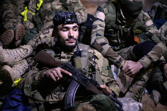 Fighters from Hayat Tahrir Al-Sham (HTS) gather at a position in the eastern outskirts of the town of Atarib, in Syria’s northern province of Aleppo on Nov. 27, 2024, during clashes with the Syrian army. (AFP)