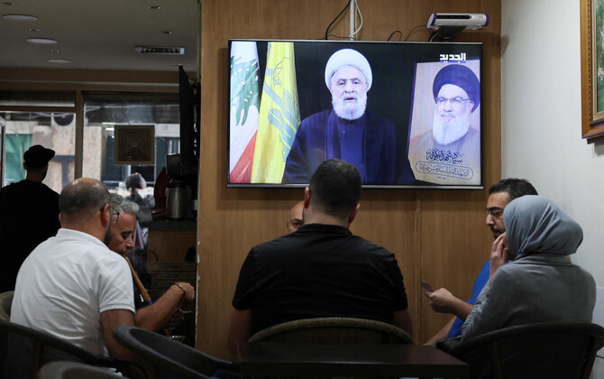 People sit in a cafe as they listen to Lebanon’s Hezbollah new leader Sheikh Naim Qassem delivering a televised address, in Beirut, on Nov. 6, 2024. (Reuters)