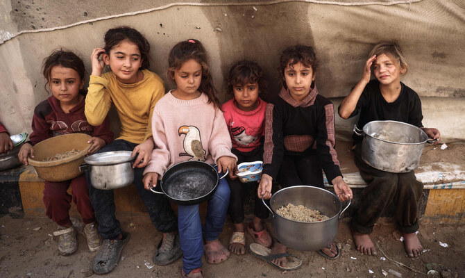 Palestinian children collect food from a distribution center at Bureij refugee camp in the central Gaza City amid the ongoing Israeli onslaught in the besieged territory. (AFP)