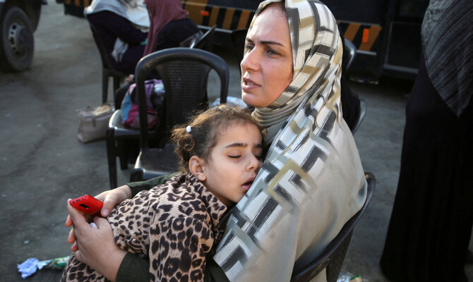 A Palestinian woman holds a sleeping child as people say goodbye to patients and the wounded before they are transferred for medical treatment abroad, amid the Israel-Hamas conflict, in Khan Younis in the southern Gaza Strip, November 6, 2024. (Reuters)