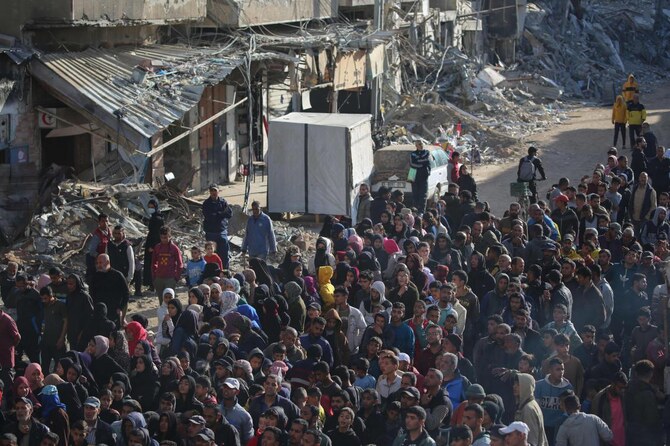 A huge crowd of people waits amid the destruction for fresh bread outside a bakery in the southern Gaza city of Khan Yunis on Nov. 20, 2024. (AFP)
