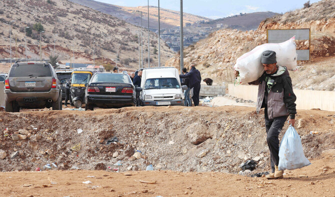 A man fleeing Israeli bombardment crosses a crater, caused by an airstrike, in the area of Masnaa on the Lebanese side of the border crossing with Syria. (AFP)