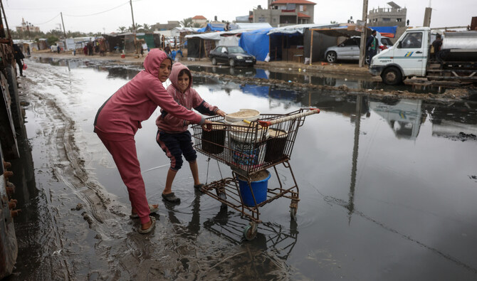 Displaced Palestinian children transport sand from the nearby beach to be used for making sand bags for protecting tents from the rain, following heavy rainfall north of Deir El-Balah in the central Gaza Strip on November 24, 2024. (AFP)