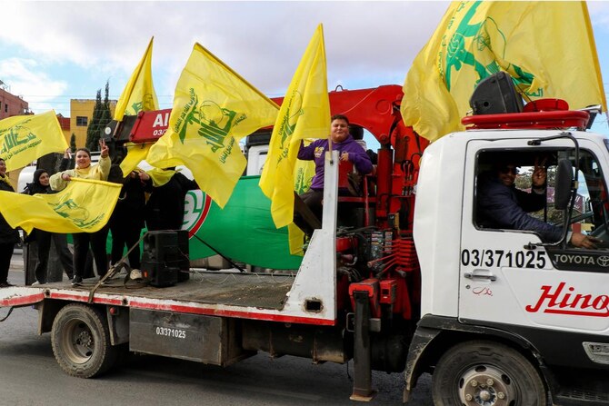 People wave the flag of the Lebanese movement Hezbollah as residents return to the city of Baalbek on Nov. 27, 2024, after a ceasefire between Hezbollah and Israel took effect. (AFP)